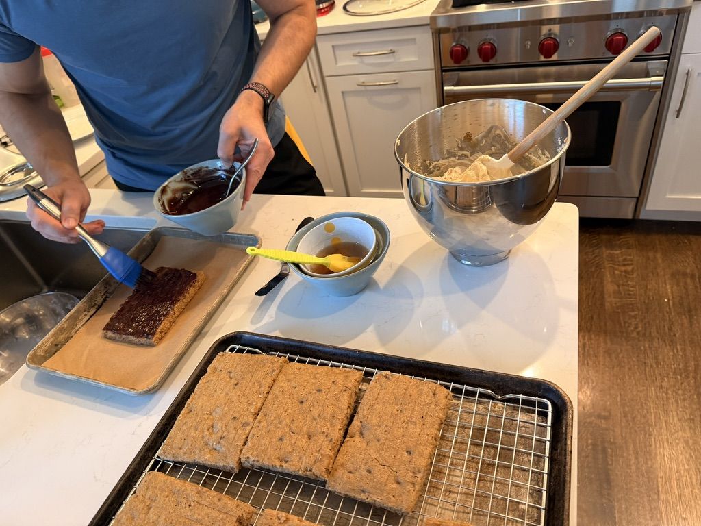 Brushing a thin layer of dark chocolate ganache onto a cake bar