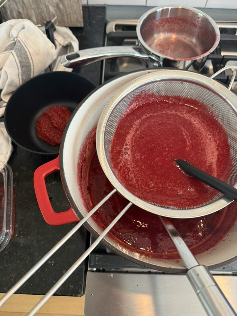 Straining the jelly through a fine mesh strainer