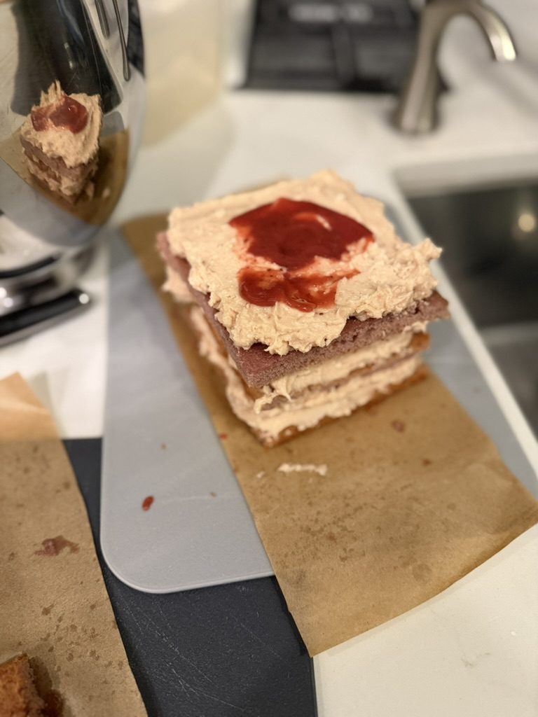 A swirl of red strawberry reduction over buttercream on a layer