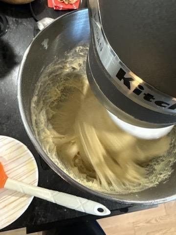 The enriched dough mid-knead in the mixer, looking greasy before it comes smooth